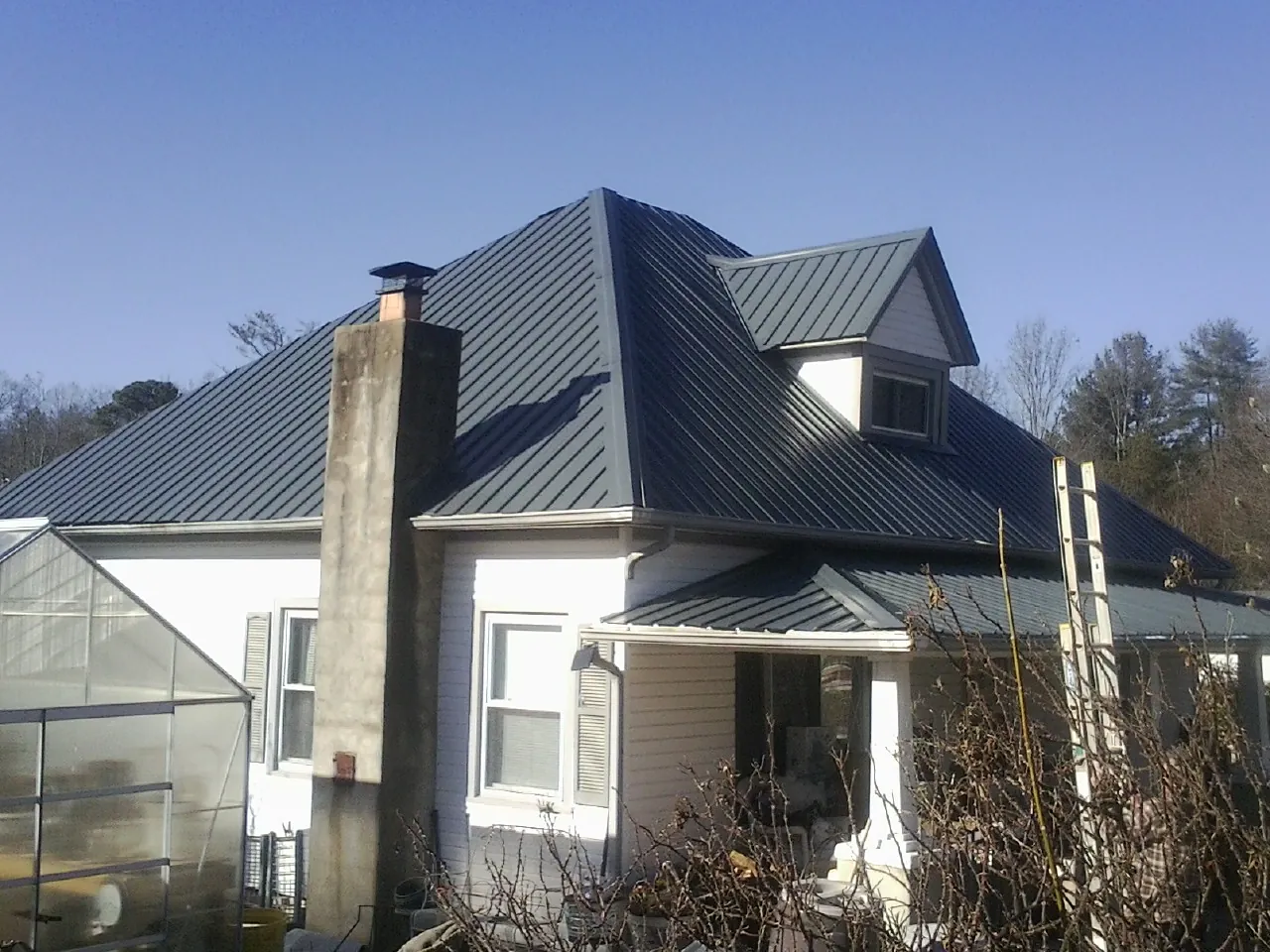 Dark blue standing seam metal roof on a white farmhouse with dormer — Slate & Tile Roof Repair by Roofing Brothers in Mechanicstown