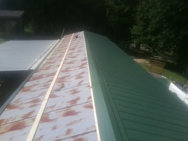 Old rusted panels beside newly installed green metal roofing — Wind Damage Roof Repair by Roofing Brothers in Mechanicstown
