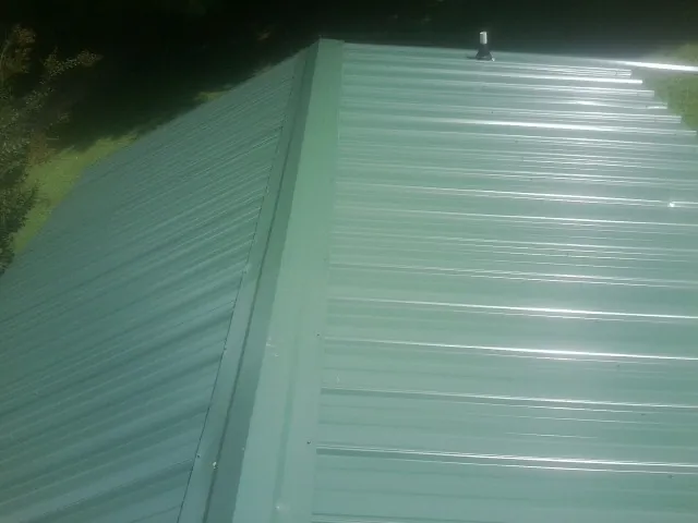 New green metal panels meeting at the ridge of a roof — Flat Roof Repair work by our crew in Mechanicstown
