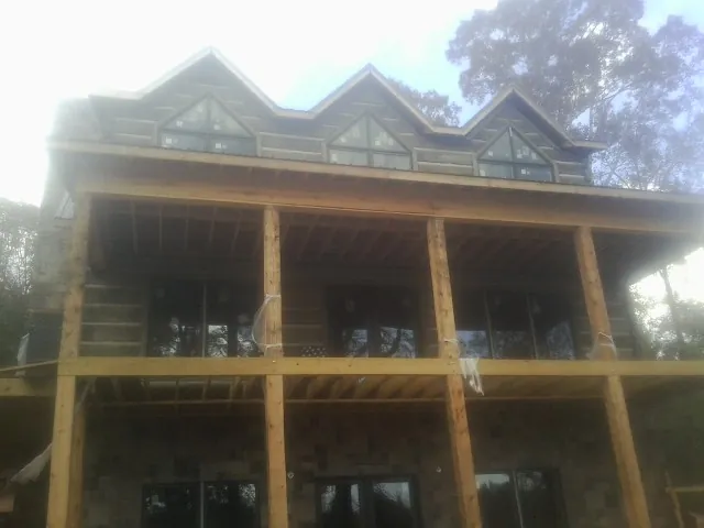 Dormers and porch framing on a large log home under construction — Roof Coating work by our crew in Mechanicstown