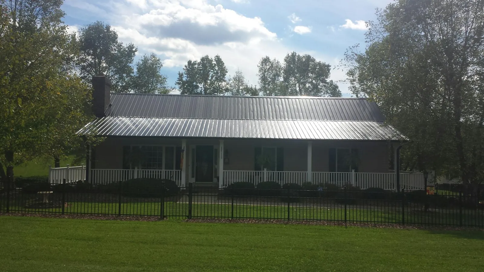 Gray metal roof on a brick ranch with a full width front porch — Gutter Guard Installation work by our crew in Mechanicstown