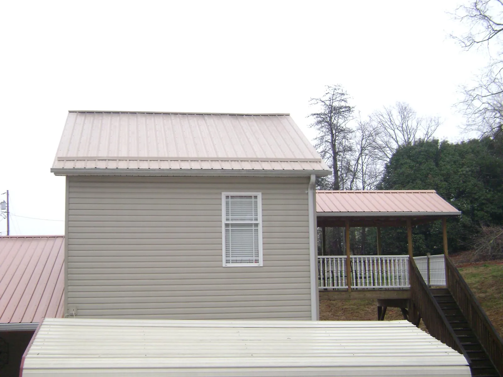 Tan metal roofs on a two story addition and attached porch, from a Roof Replacement job in Mechanicstown