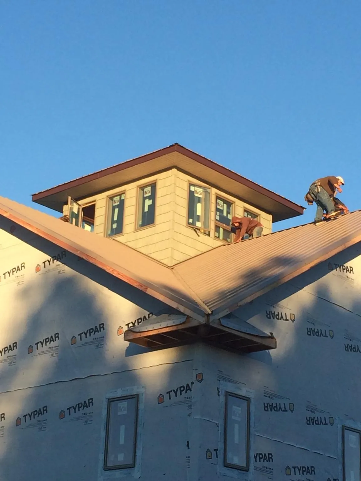 Roofers working around a rooftop cupola on a new metal roof at sunset — Roof Waterproofing in Mechanicstown by Roofing Brothers